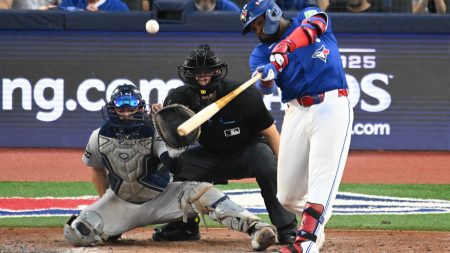 Oct 4, 2025; Toronto, Ontario, CAN; Toronto Blue Jays first baseman Vladimir Guerrero Jr. (27) hits a RBI sacrifice fly in the seventh inning in front of New York Yankees catcher Austin Wells (28) during game one of the ALDS round for the 2025 MLB playoffs at Rogers Centre.
