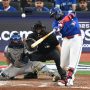 Oct 4, 2025; Toronto, Ontario, CAN; Toronto Blue Jays first baseman Vladimir Guerrero Jr. (27) hits a RBI sacrifice fly in the seventh inning in front of New York Yankees catcher Austin Wells (28) during game one of the ALDS round for the 2025 MLB playoffs at Rogers Centre.