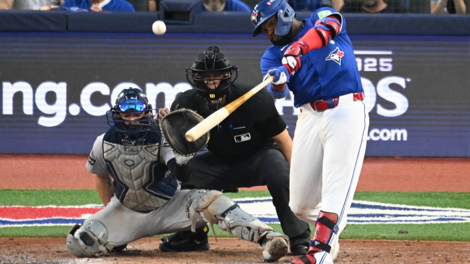Oct 4, 2025; Toronto, Ontario, CAN; Toronto Blue Jays first baseman Vladimir Guerrero Jr. (27) hits a RBI sacrifice fly in the seventh inning in front of New York Yankees catcher Austin Wells (28) during game one of the ALDS round for the 2025 MLB playoffs at Rogers Centre.