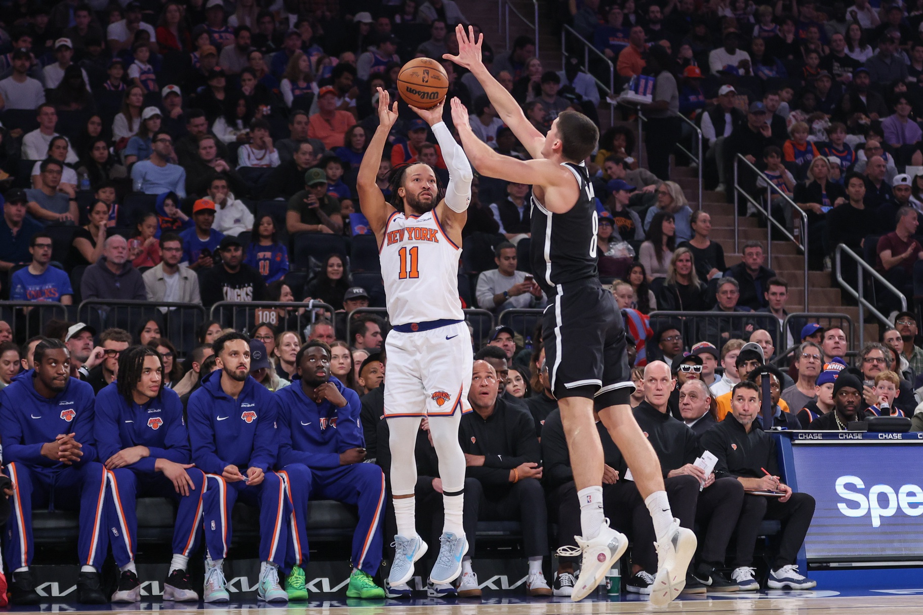 Nov 9, 2025; New York, New York, USA; New York Knicks guard Jalen Brunson (11) takes a three point shot past Brooklyn Nets guard Egor Demin (8) in the first quarter at Madison Square Garden.