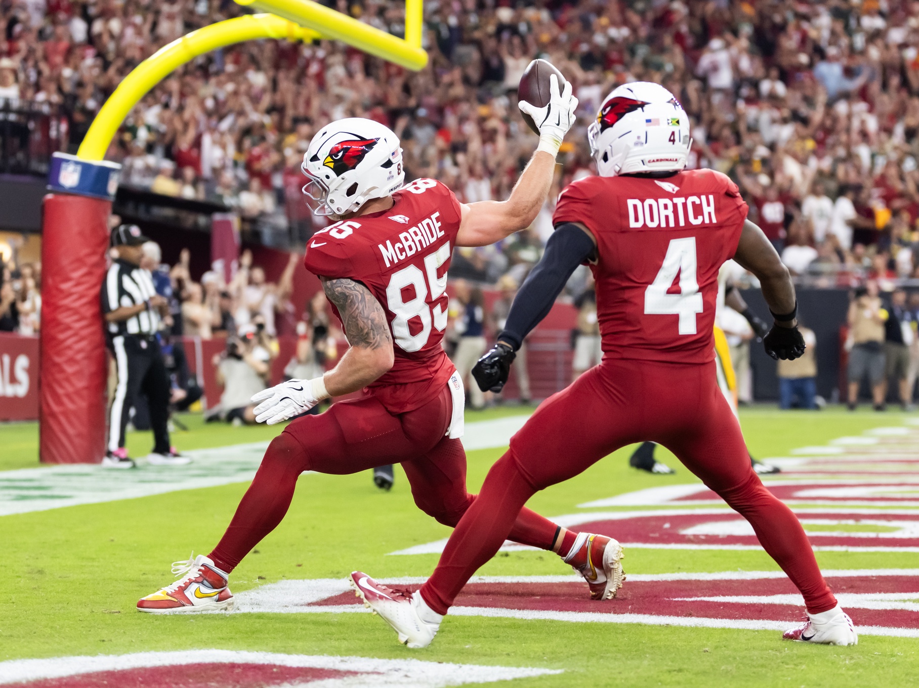 Oct 19, 2025; Glendale, Arizona, USA; Arizona Cardinals tight end Trey McBride (85) spikes the ball as he celebrates a touchdown with teammate Greg Dortch (4) against the Green Bay Packers in the second half at State Farm Stadium.