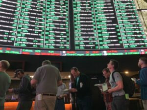 Bettors look over Super Bowl prop sheets while lined up to bet at The SuperBook, ahead of the Chiefs-Buccaneers clash in February 2021. Looming above is The SuperBook's monster betting board, listing the prop bets.