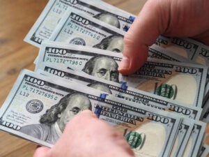 Hands are seen counting through a stack of $100 U.S. bills