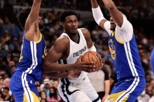 Memphis Grizzlies forward Jaren Jackson Jr., center, looks for an opening with both hands on the ball between the outstretched arms of the Golden State Warriors' Andrew Wiggins, left, and Kevon Looney, right, on Sunday, May 1, 2022, in Memphis, Tenn.