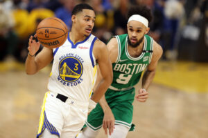 Golden State Warriors guard Jordan Poole (left) dribbles the basketball with his right hand as Boston Celtics guard Derrick White (right) pursues from behind during Game 1 of the 2022 NBA Finals