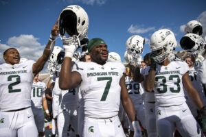 Michigan State Spartans players salute fans in the stands