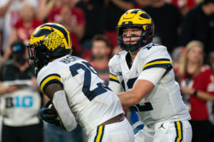 Michigan Wolverines quarterback Cade McNamara hands off the ball to running back Hassan Haskins