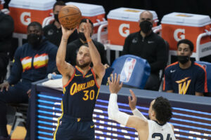 Golden State Warriors guard Stephen Curry takes a shot over an opponent