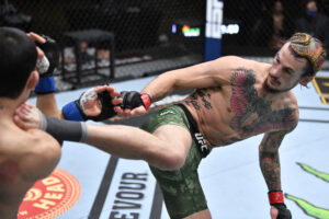 UFC fighter Sean O'Malley (right) kicks opponent Thomas Almeida in their bantamweight fight during UFC 260