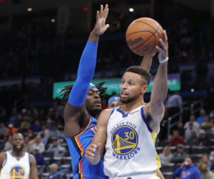 Golden State Warriors guard Stephen Curry (right) passes the ball around Oklahoma City Thunder forward Luguentz Dort (left)