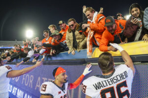 Oklahoma State Cowboys players celebrate with fans after defeating the West Virginia Mountaineers