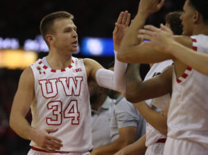 Wisconsin Badgers guard Brad Davison celebrates with teammates after returning to the bench near the end of a game against the Marquette Golden Eagles