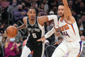 San Antonio Spurs guard Dejounte Murray dribbles the basketball as he attempts to drive against Phoenix Suns guard Landry Shamet