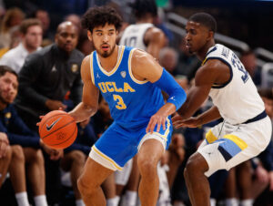 UCLA Bruins guard Johnny Juzang (left) dribbles the basketball during agame against the Marquette Golden Eagles