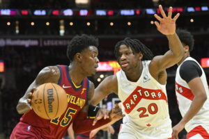 Cleveland Cavaliers forward Trevon Scott (left) dribbles the basketball with his right hand as he tries to get past defending Toronto Raptors center Daniel Oturu (right)