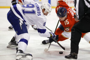 Florida Panthers center Anton Lundell (right) and Tampa Bay Lightning center Steven Stamkos (left) swipe at the puck with their sticks during a face-off