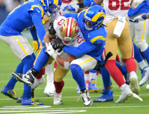 San Francisco 49ers running back Eli Mitchell (25) is stopped by Los Angeles Rams defensive back Terrell Burgess (26) after a 9-yard gain