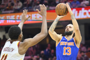 New York Knicks guard Evan Fournier (right) takes a shot over Cleveland Cavaliers center Evan Mobley (left)