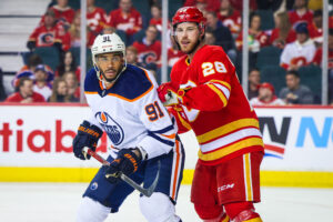 Edmonton Oilers left wing Evander Kane (left) and Calgary Flames center Elias Lindholm (right) fight for position while eyeing the puck