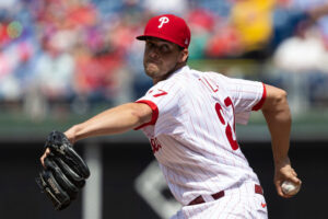 Philadelphia Phillies right-handed starting pitcher Aaron Nola grips the baseball with his right hand behind his back and prepares to throws a pitch against the New York Mets