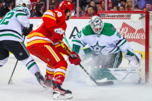 Dallas Stars goaltender Jake Oettinger (right) makes a save against Calgary Flames left wing Andrew Mangiapane (middle) during a 2022 Stanley Cup Playoffs game