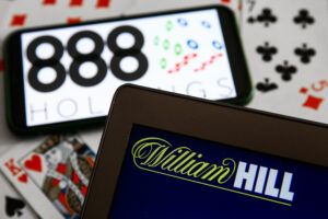 888 Holdings logo displayed on a mobile phone, William Hill logo displayed on a laptop screen 